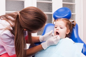 Young child (girl) that is having her mouth looked at by a dental hygienist