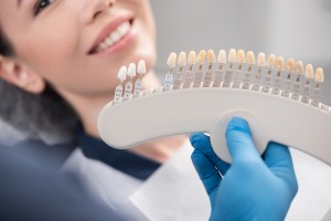 A woman patient that is being shown all the different shades of porcelain veneers she can have on her teeth.