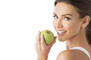 Woman smiling towards the camera as she goes to eat an apple.