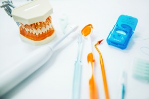 A collection of oral health products that include a toothbrush, electric toothbrush, floss, mouth model, and dental tools. 