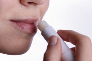 Happy smiling Woman applying lip balm close up. Beauty, winter skin care concept