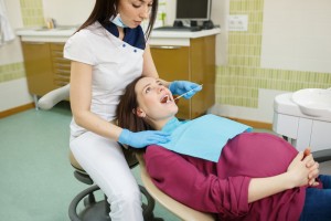 Pregnant woman having her mouth looked at by a dental hygienist.