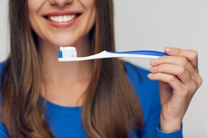 Close-up view of a woman holding up a toothbrush with toothpaste on it that she is about to use.