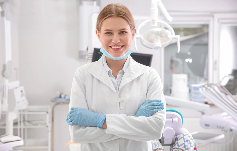 Young female periodontist standing in dental office.